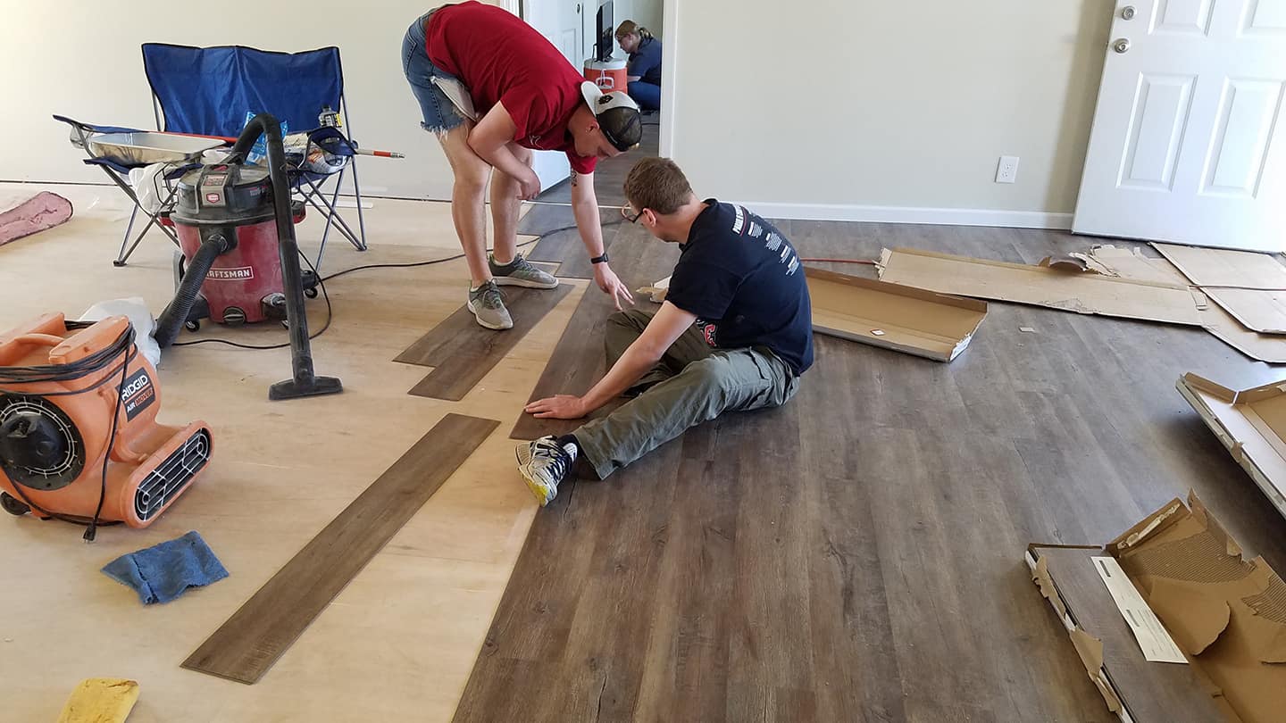 College students lay flooring in a homeowner's house that was ruined by Hurricane Florence.