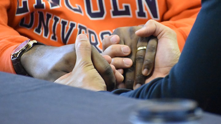 Two people hold hands to pray