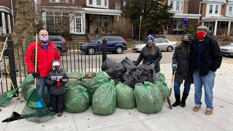 Four Watershed Church members standing in school yard with bags of trash collected during school cleanup