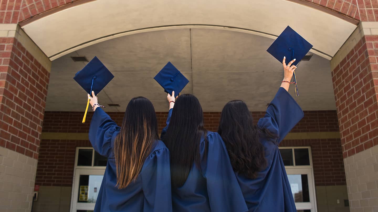 Graduates holding up caps