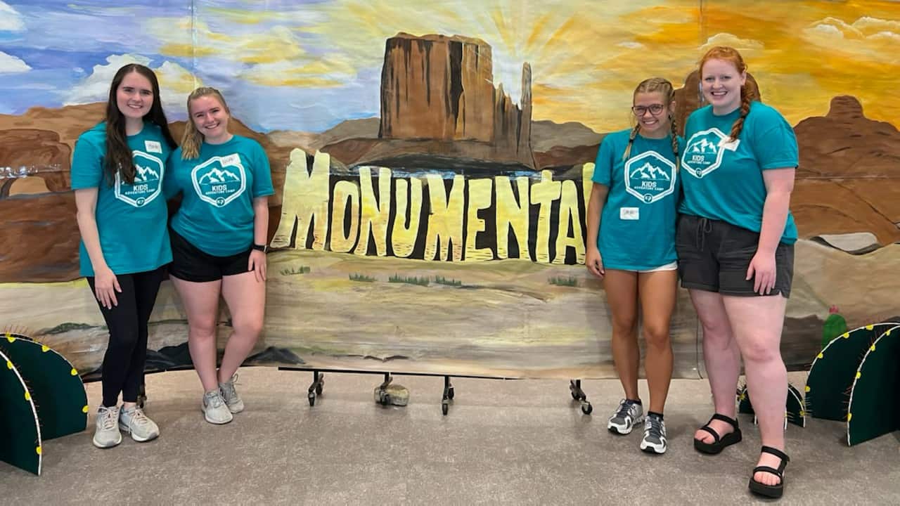 Interns in front of VBS backdrop that says Monumental