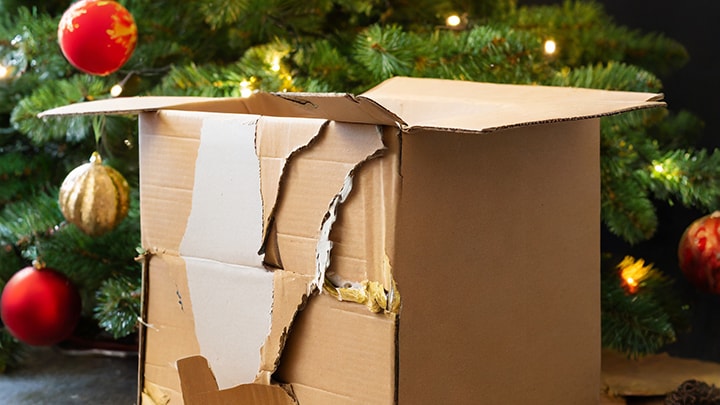 Damaged Cardboard Box In Front Of Christmas Tree