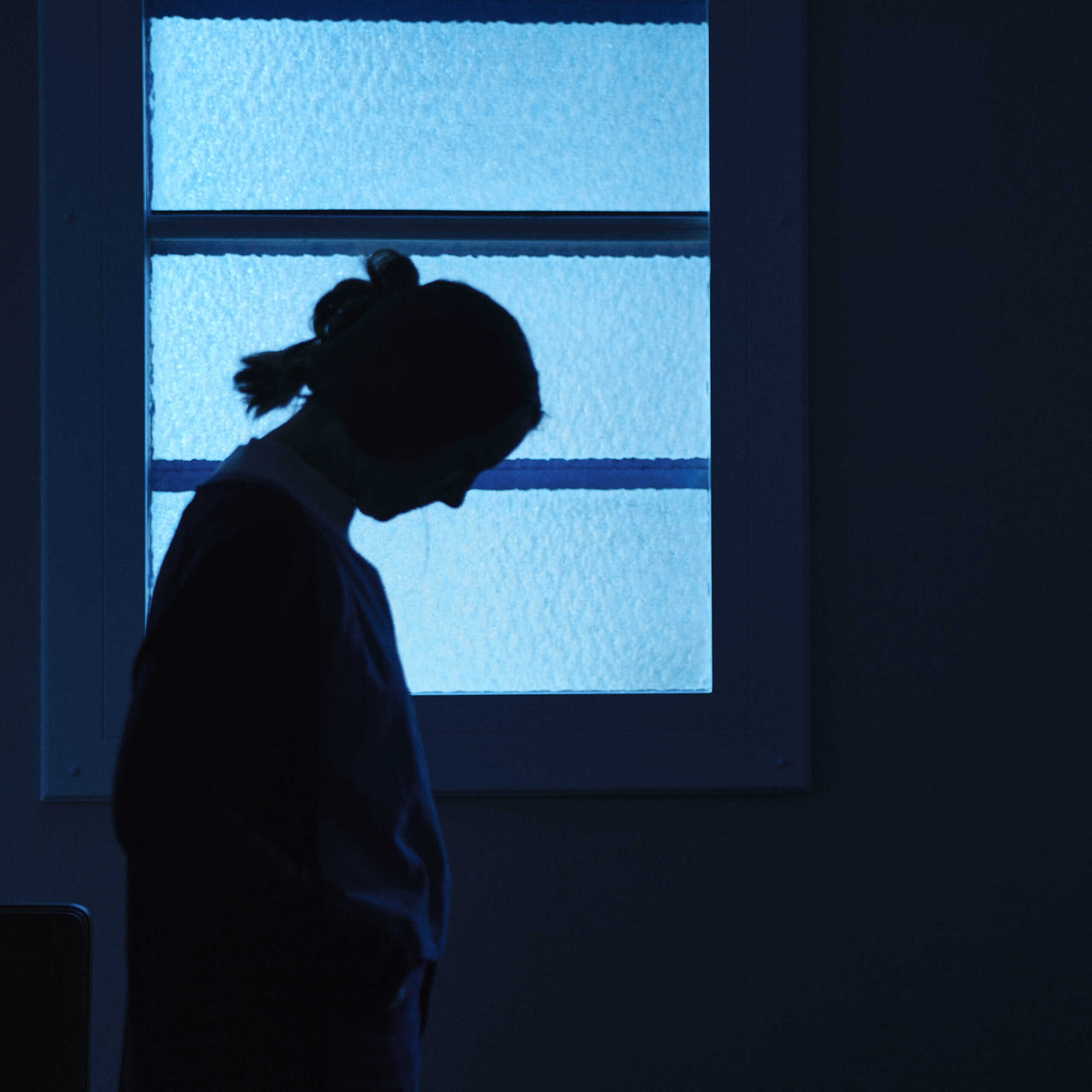 Silhouette of a person standing in front of a window