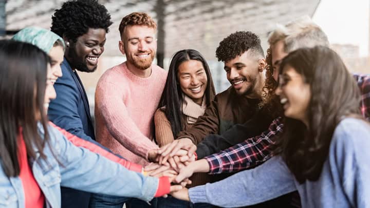 Young multiracial friends stacking hands together